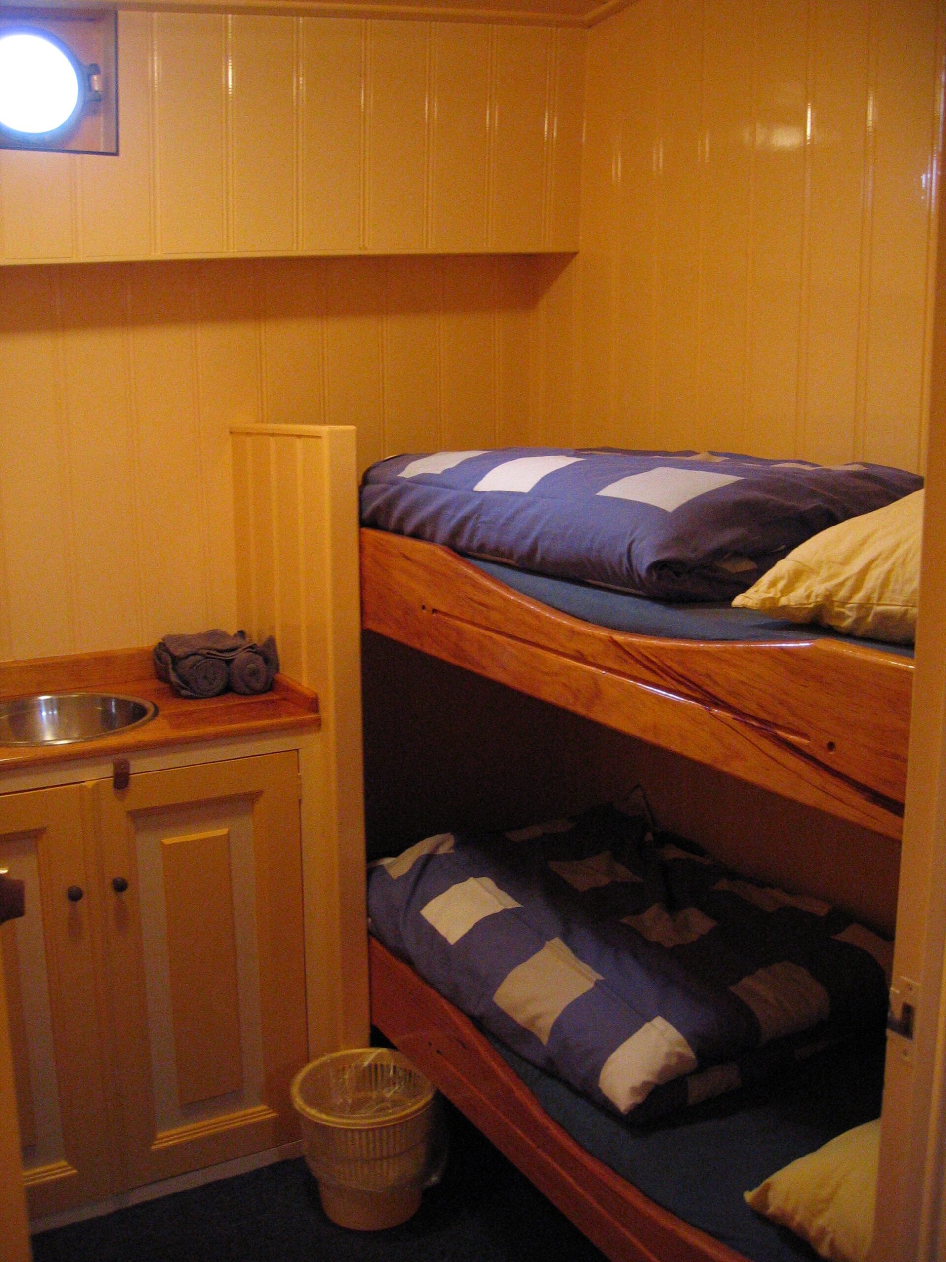 Een slaapkamer met wasbak en stapelbed voor twee personen aan boord van het historische zeilschip Frans Horjus.