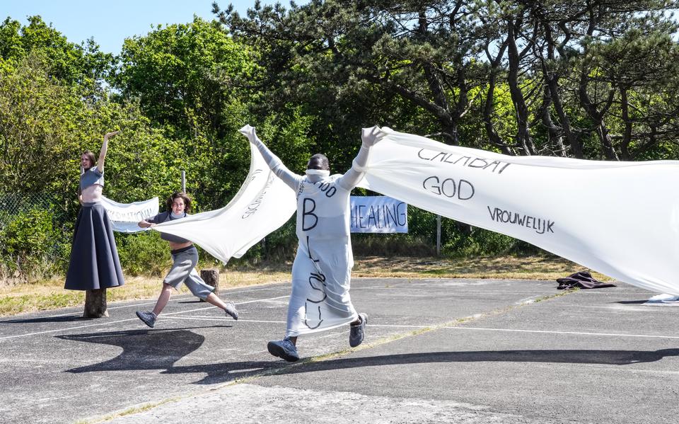 Drie in grijs geklede acteurs met banners met protesten erop, beeld uit de theatervoorstelling Gendermonologen van Raymi Sambo Maakt gespeeld op Oerol 2023.