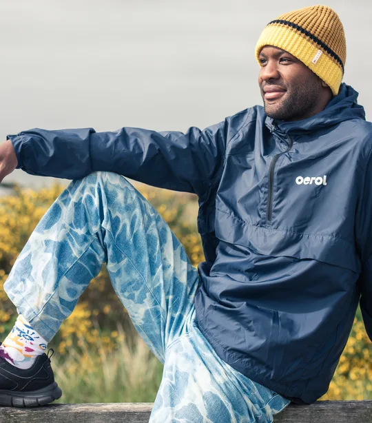 Man draagt blauwe jas en kleurrijke oerol sokken uit de Oerol merchandise collectie van 2023.