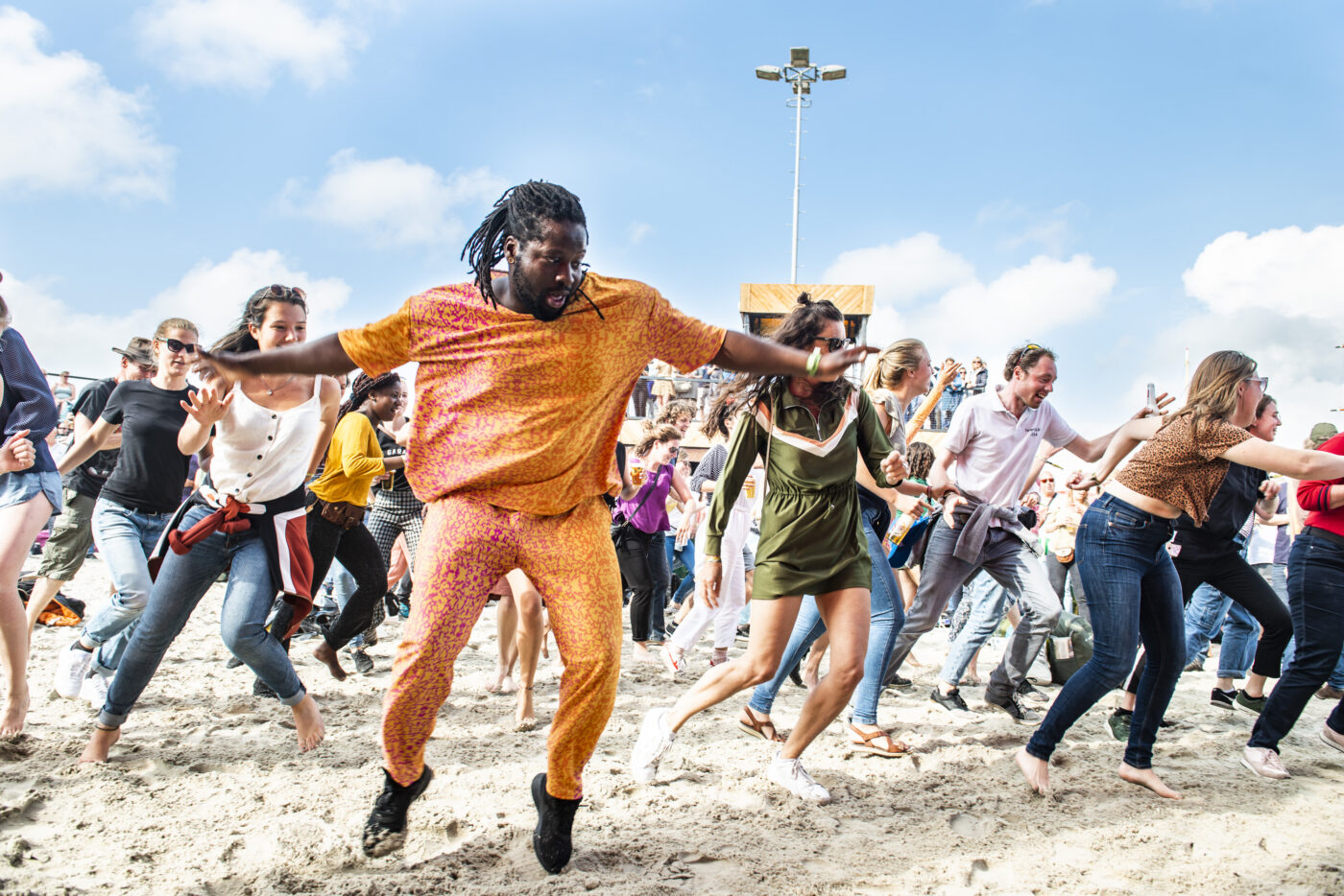 Mensen dansen in het zand op muziek van KD soundsystem op festivalterrein de Betonning tijdens Oerol 2019