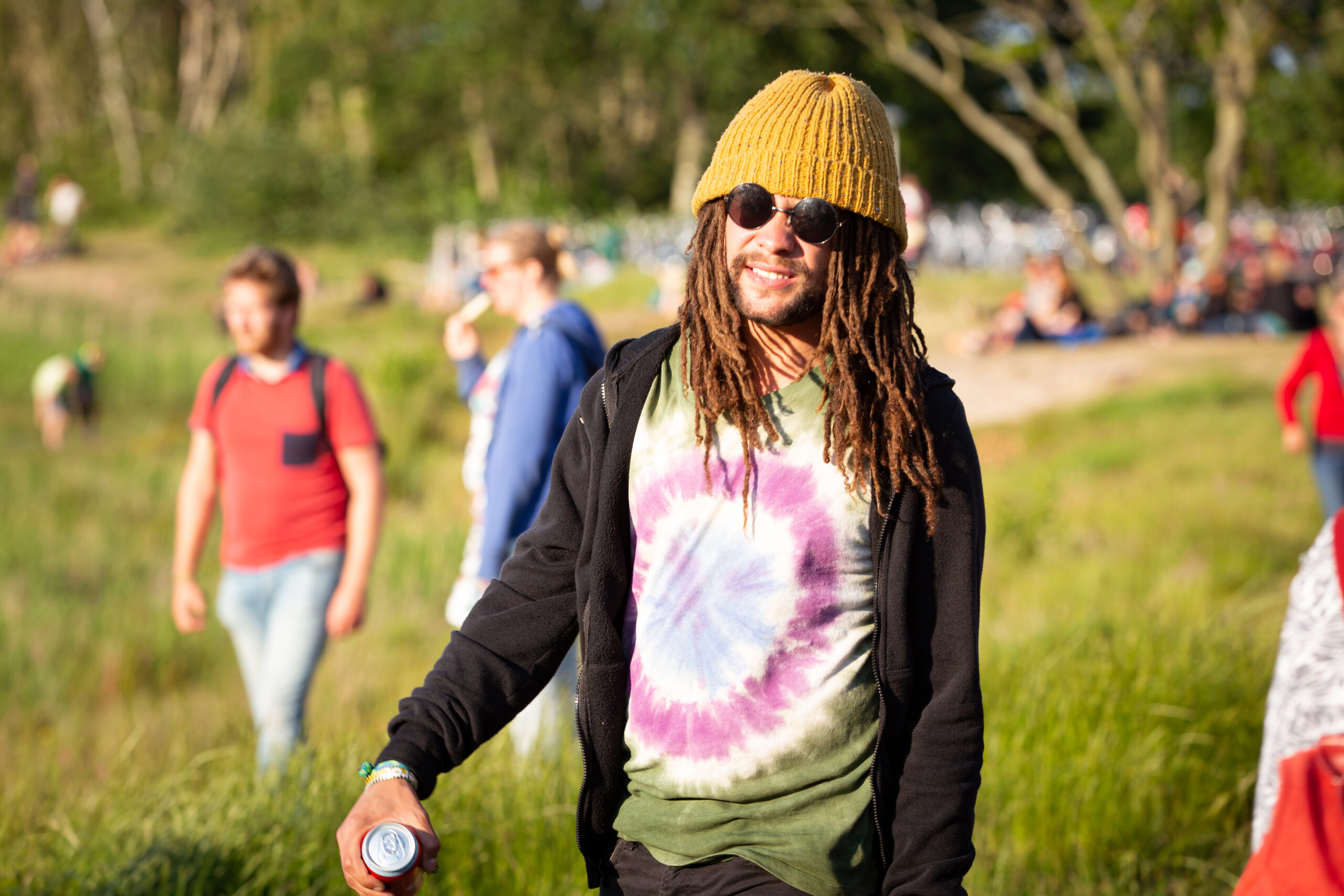een man met een gele muts en dreadlocks loopt naar een pop-feestje aan het duinmeertje van Hee tijdens Oerol 2019.