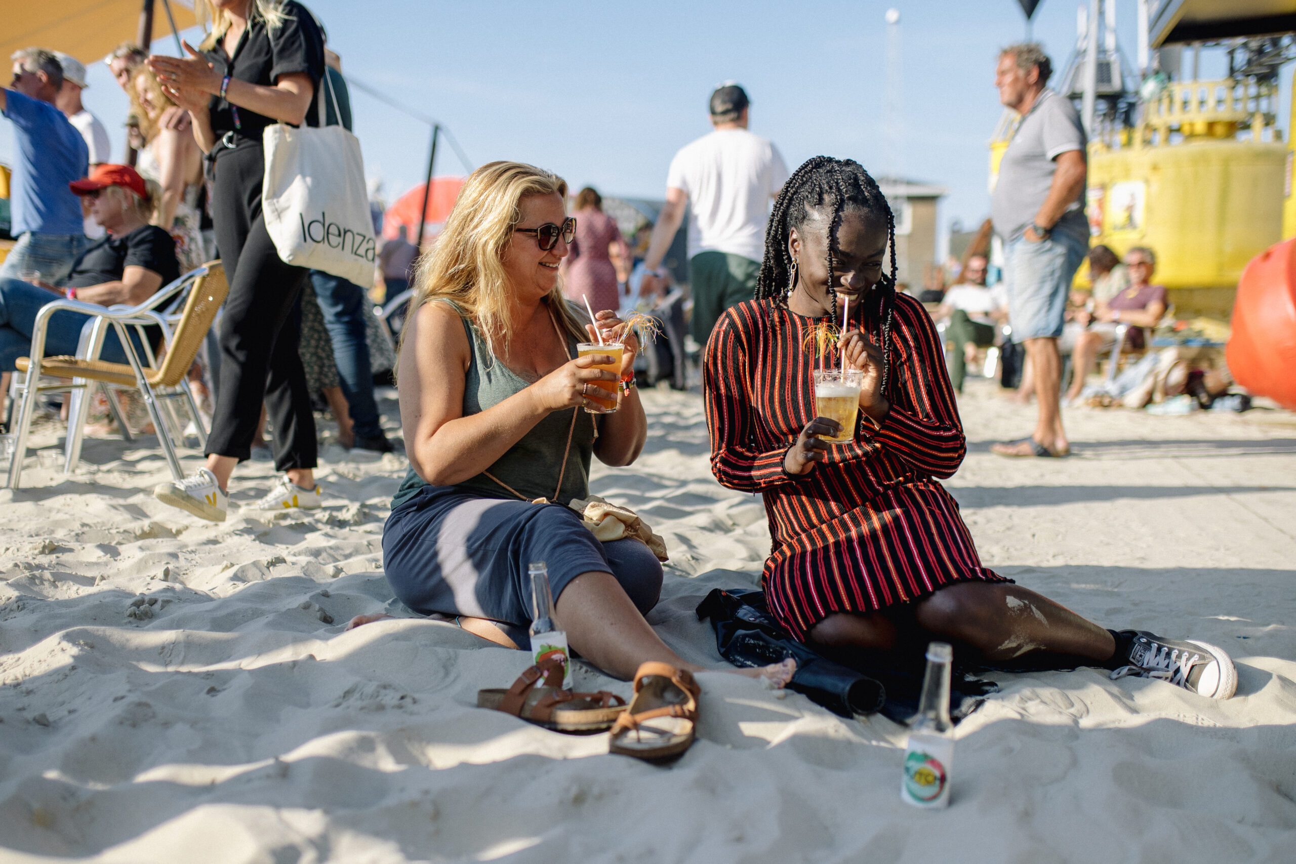 Twee vrouwen genieten van een drankje op festivalterrein de Betonning tijdens Oerol 2022.