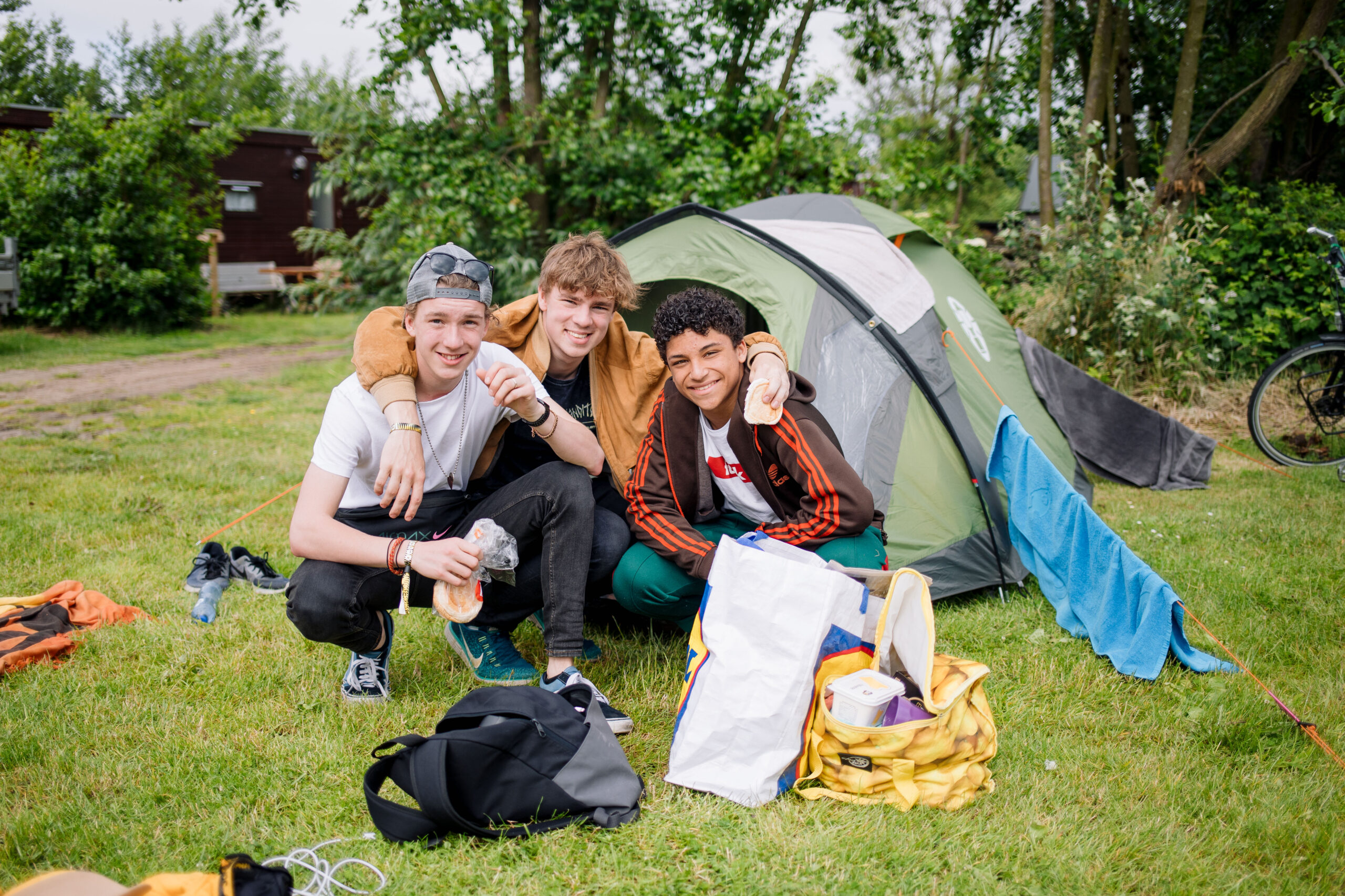 Drie jonge vrienden voor hun tent op camping De Kooi in Hee, Terschelling