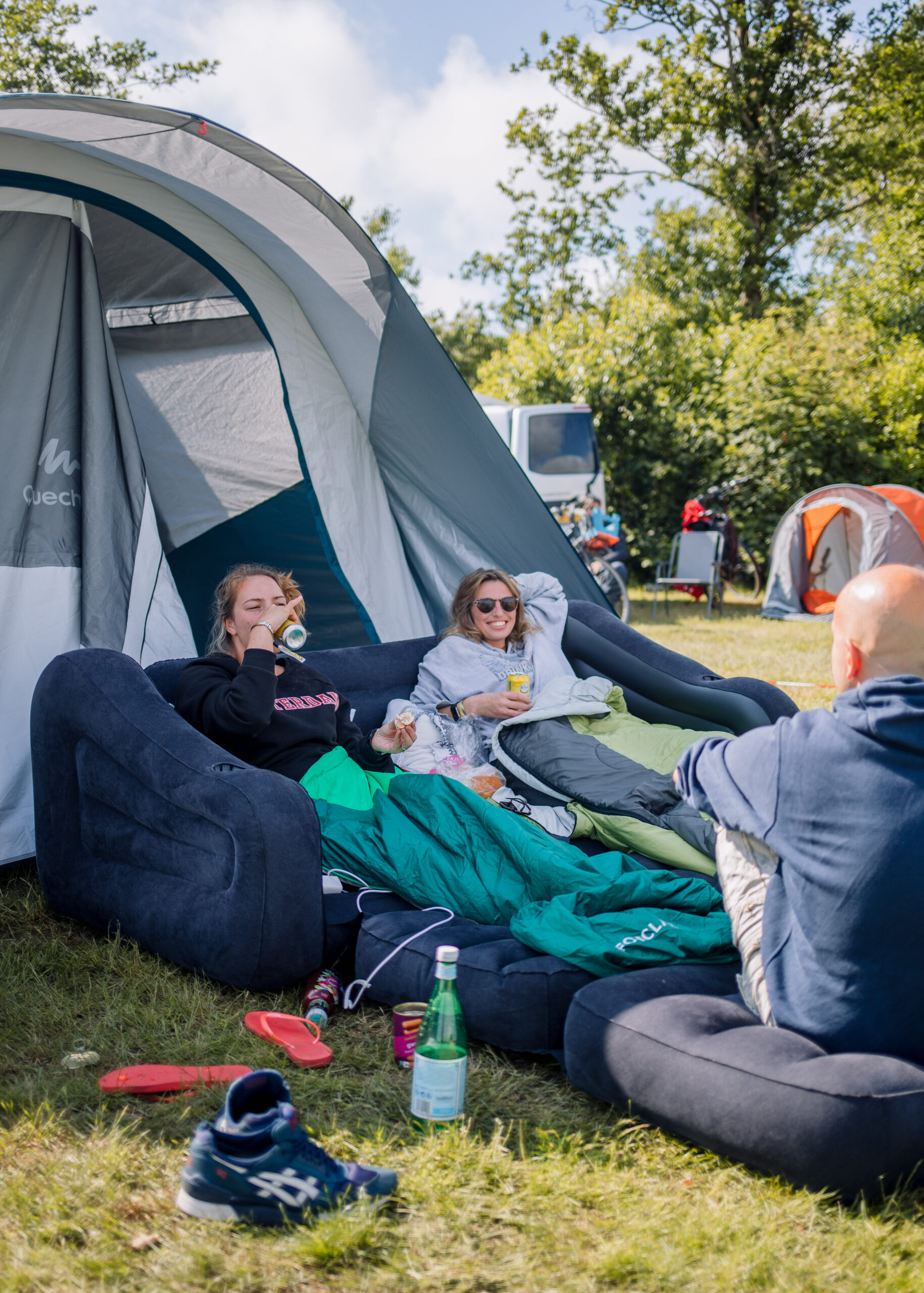 Twee jonge vrouwen zitten op een opblaasbank voor hun tent op camping de Kooi in Hee, Terschelling
