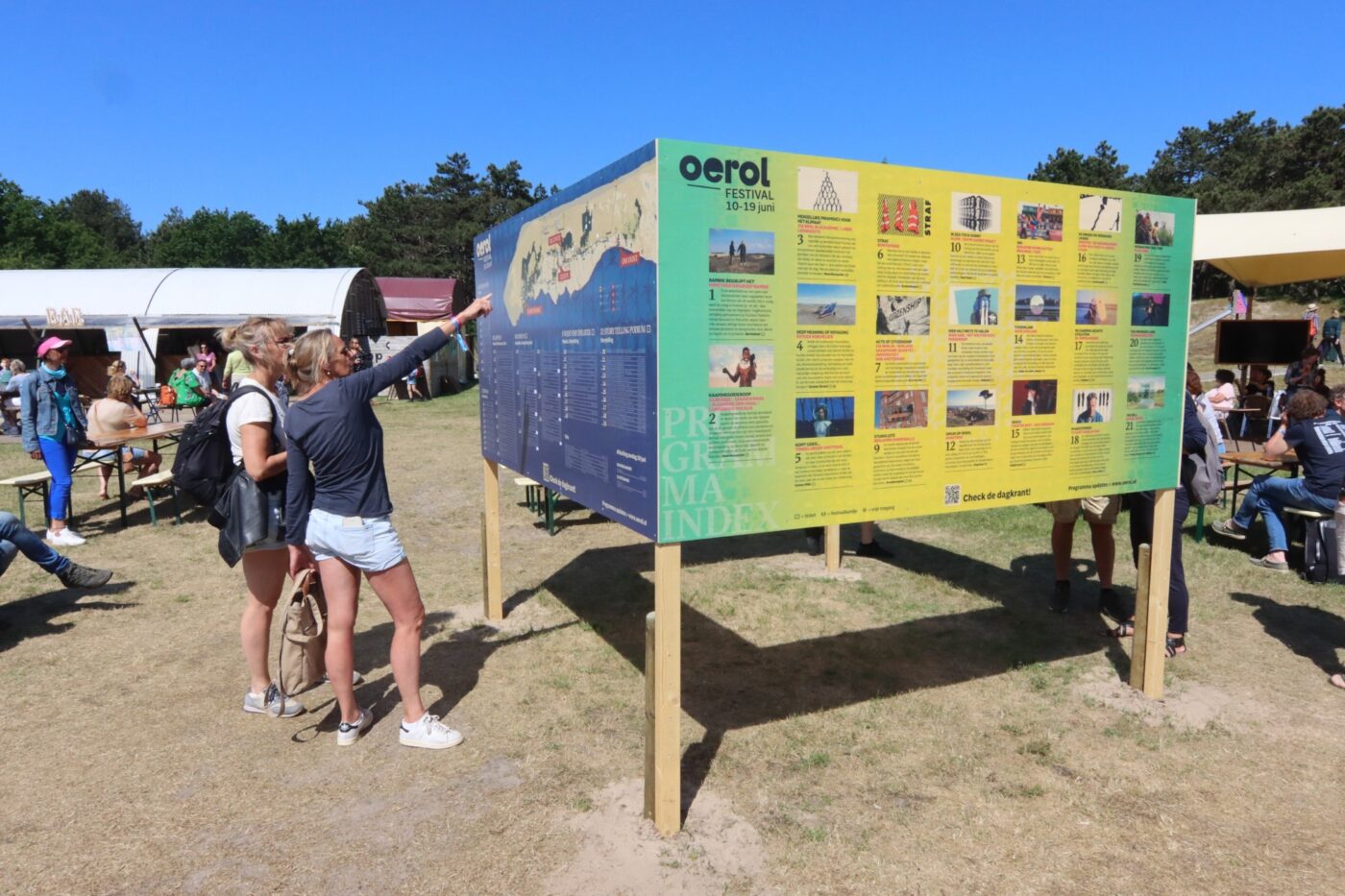 Bezoekers bekijken het programma op het festivalterrein tijdnes Oerol 2022.