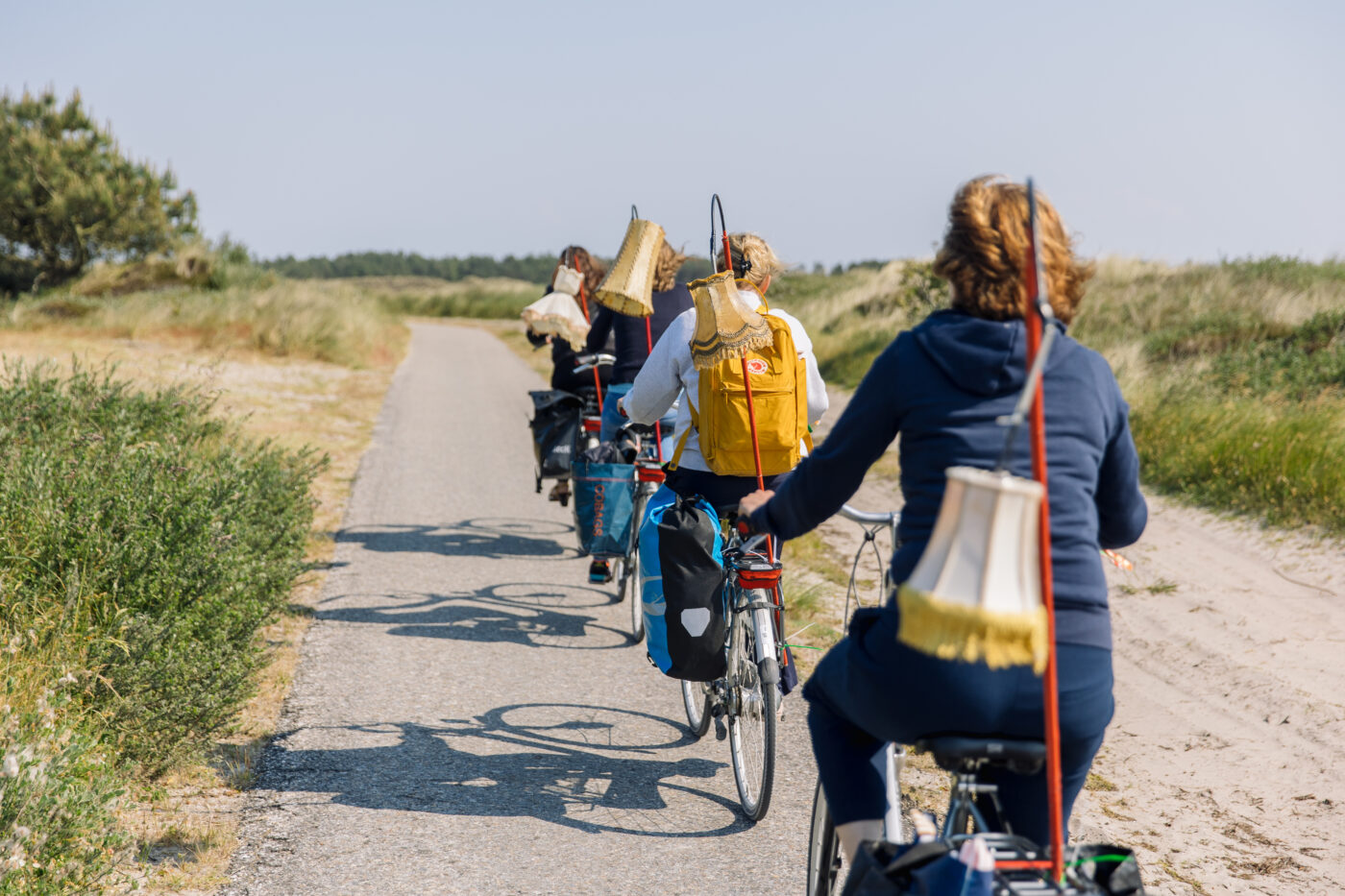 Vrouwen fietsen op fietspad op Terschelling, hun fietsen versierd met lampekapjes