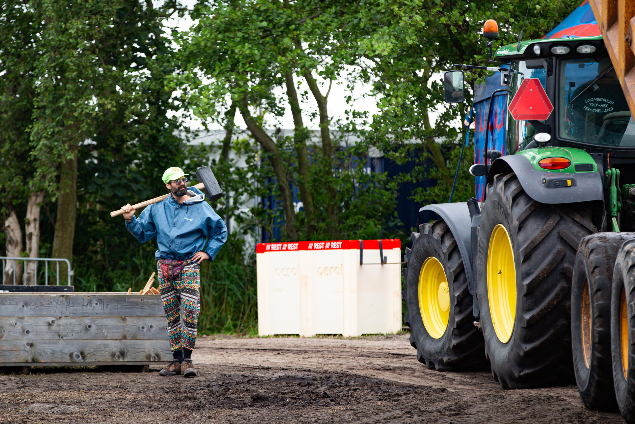 En man met een sloophamer en een tractor helpen bij de opbouw van voormalig festivalterrein de Westerkeyn op Oerol.
