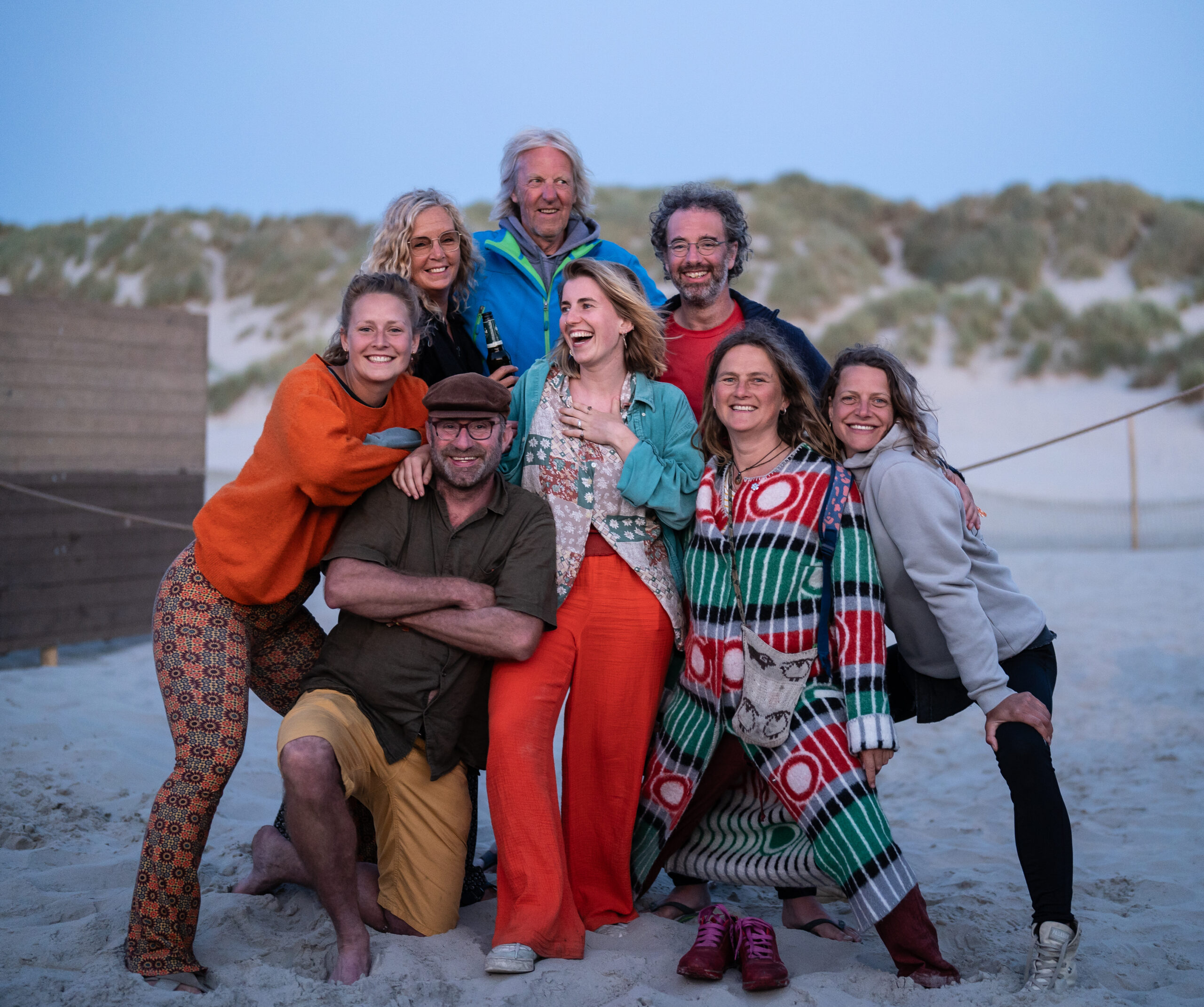 Vriendgroep van 8 mannen en vrouwen van verschillende leeftijden die lachend poseren voor de foto.