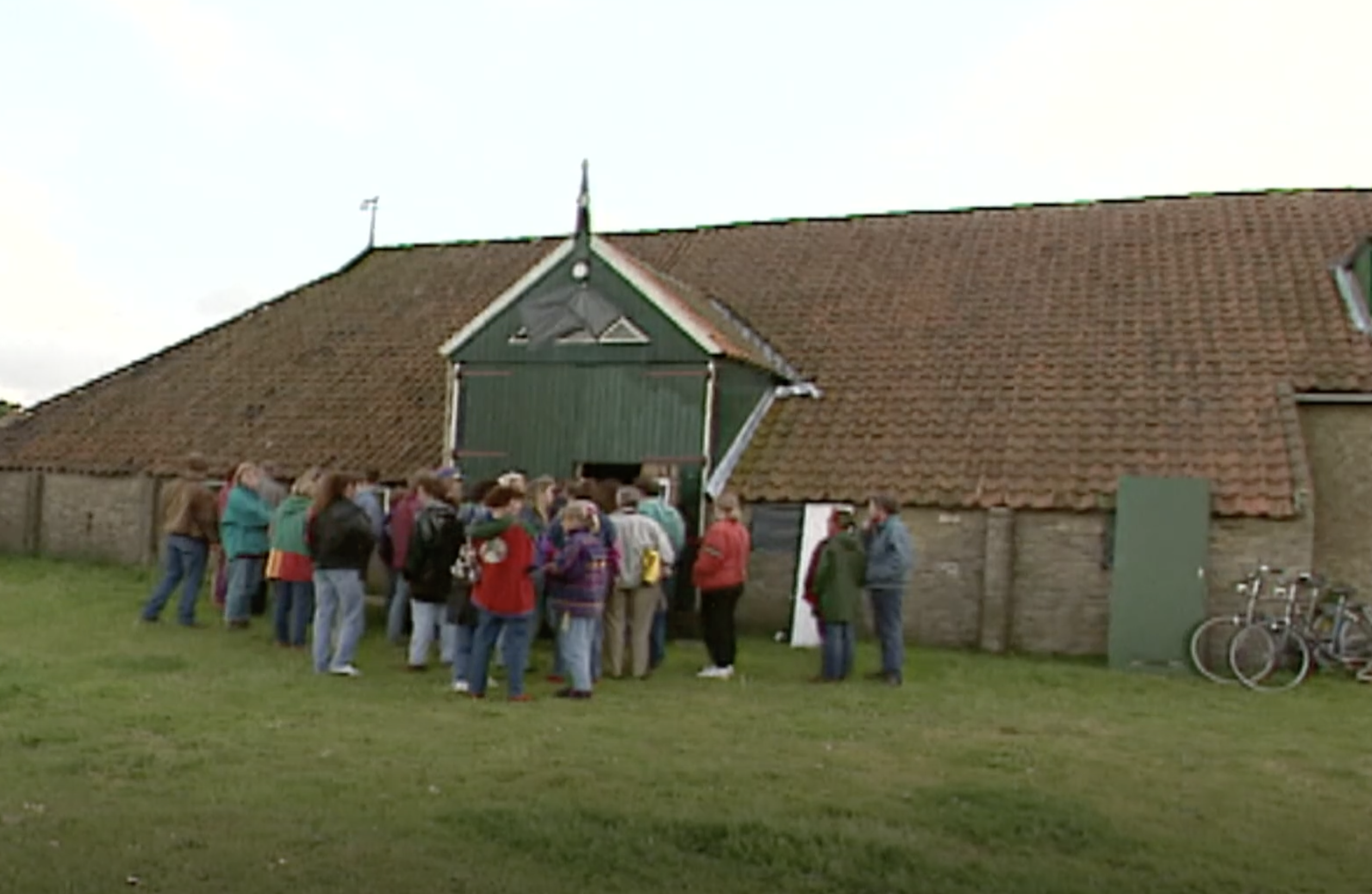 Een groep mensen loopt een oude boerenschuur in om een voorstelling te gaan bekijken op Oerol.