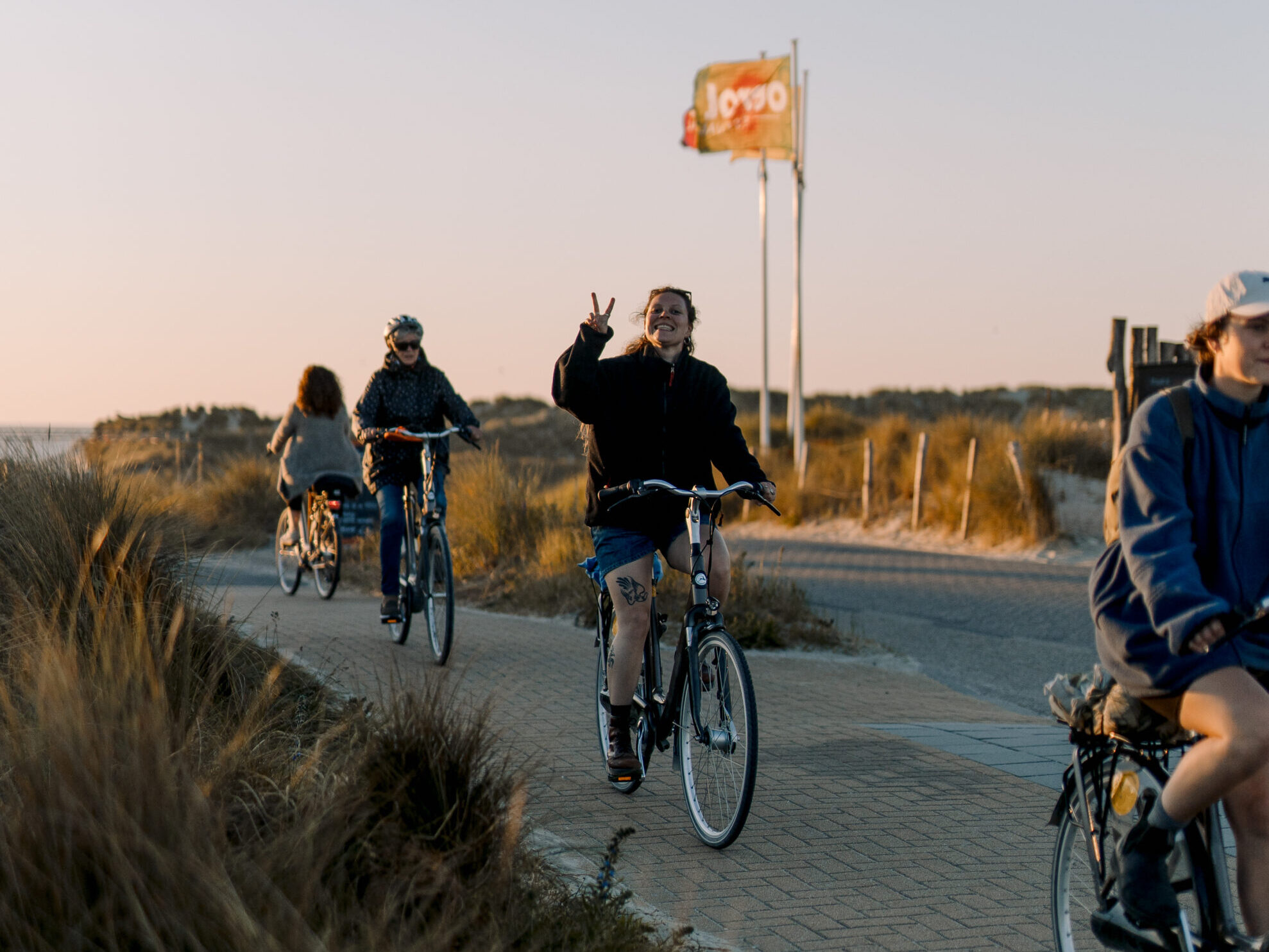 Vier jonge mensen fietsen op het fietspad vanaf festivalterrein de Deining op Oerol 2023.
