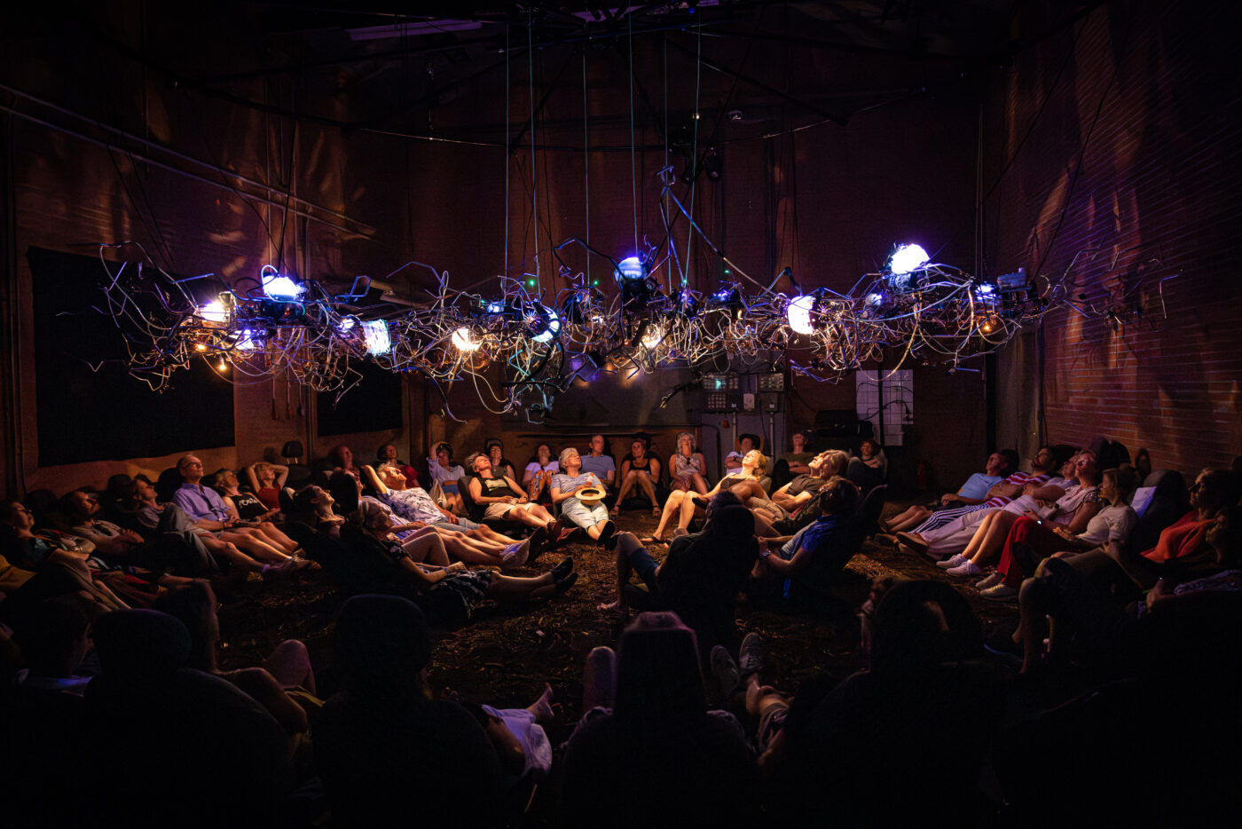 Publiek ligt in stoelen bij theatervoorstelling Transmission van het collectief Touki Delphine, een immersieve (audio)installatie en theaterervaring over de verbondenheid van alles in de natuur, Oerol 2023