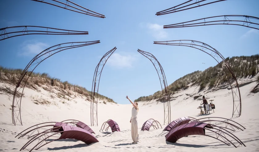Acteur Eva Meijering staat in het decor van acht grote stalen constructies die de poten van een octopus uitbeeld in de theatervoorstelling Sâlt over de strijd met jezelf en de scheiding tussen lichaam en geest, Oerol 2023