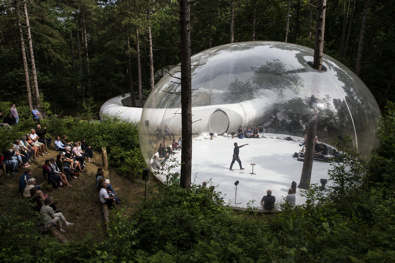 Een surrealistisch beeld van een plastic bubbel in het bos, een opgeblazen installatie behorende bij theatervoorstelling #stayout van Plastique Fantastique tijdens Oerol 2022.