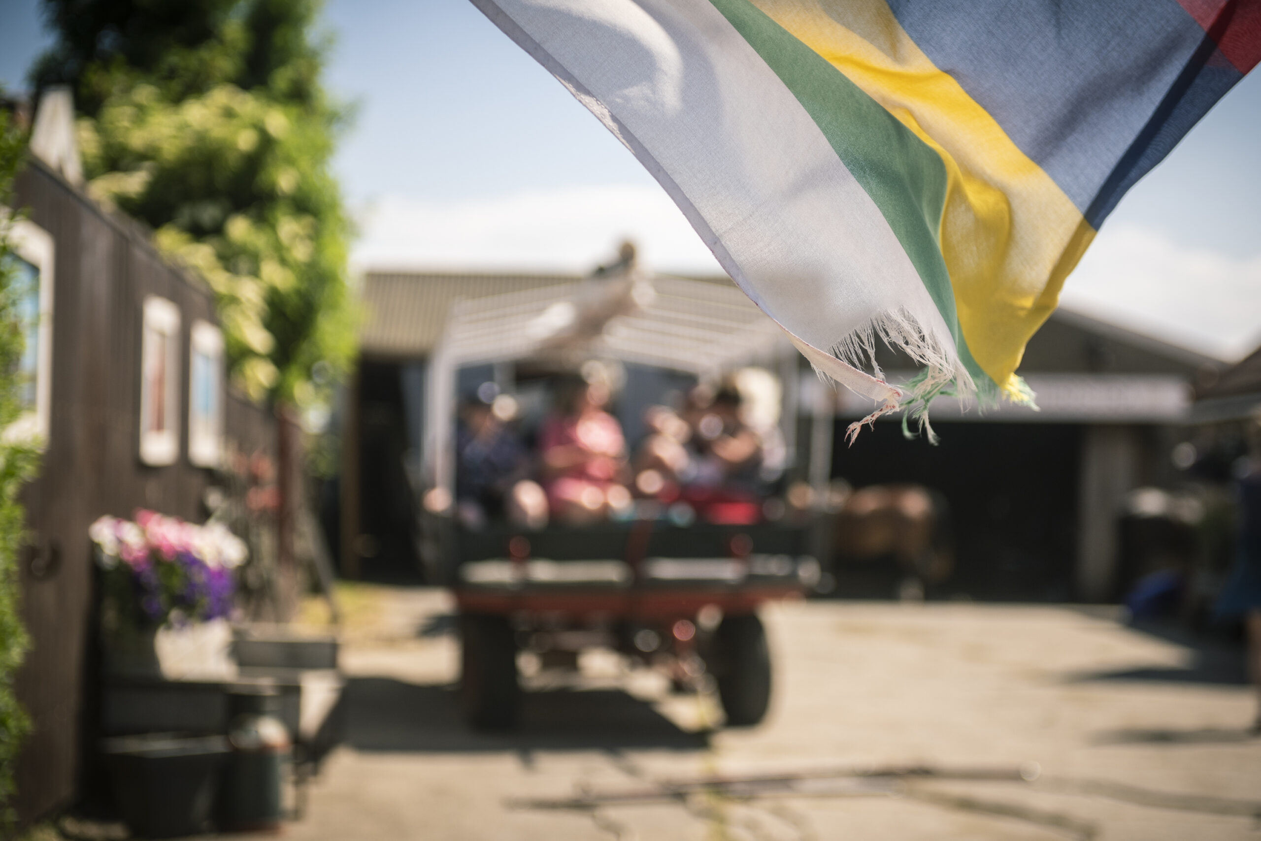 Terschellinger vlag wappert met op de achtergrond een huifkar vol mensen bij een Vriendenactie tijdens Oerol 2023