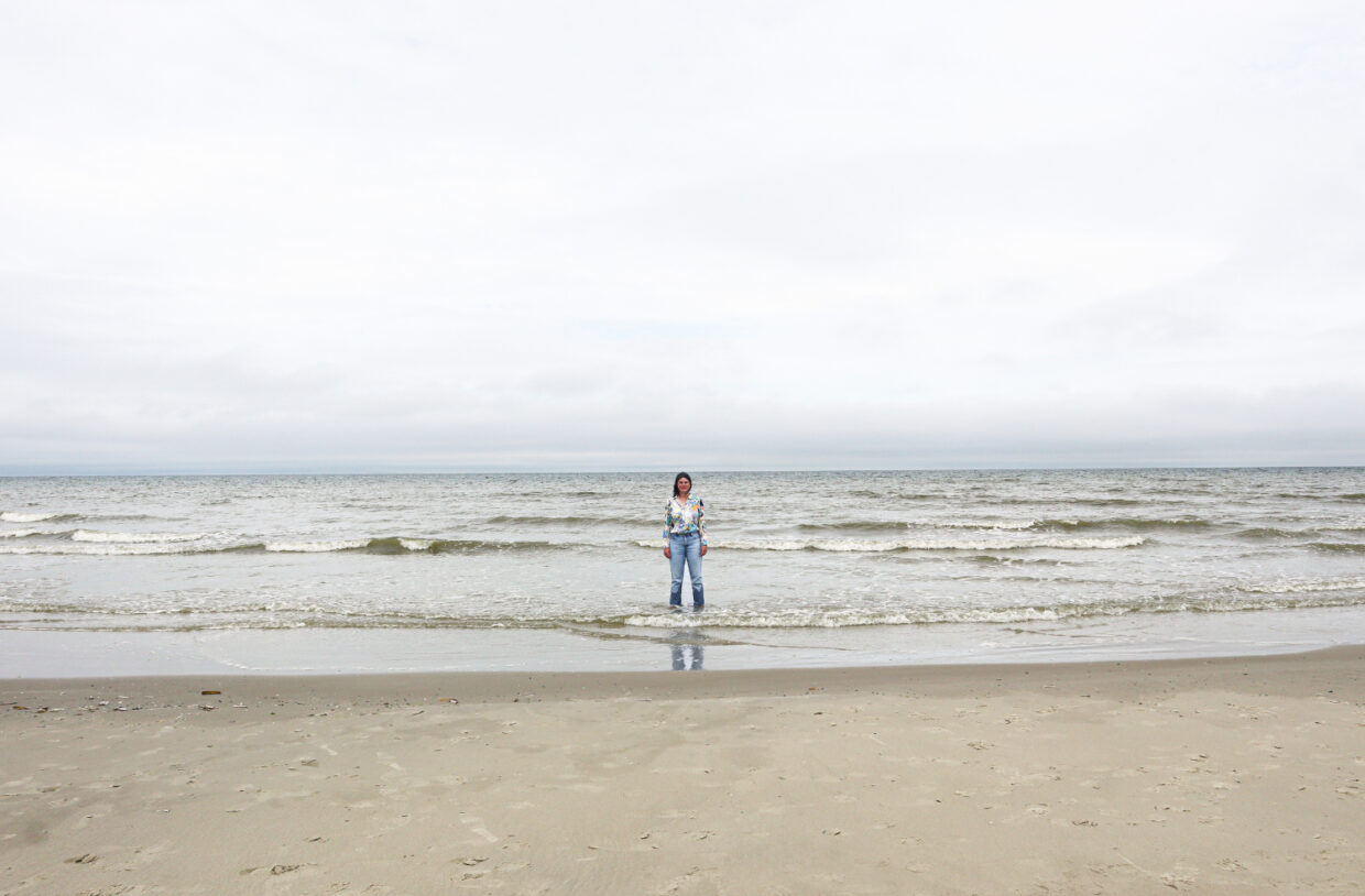 Artistiek leider van Oerol, Sabine Pater, staat met haar benen in de zee op het strand van Midsland Terschelling