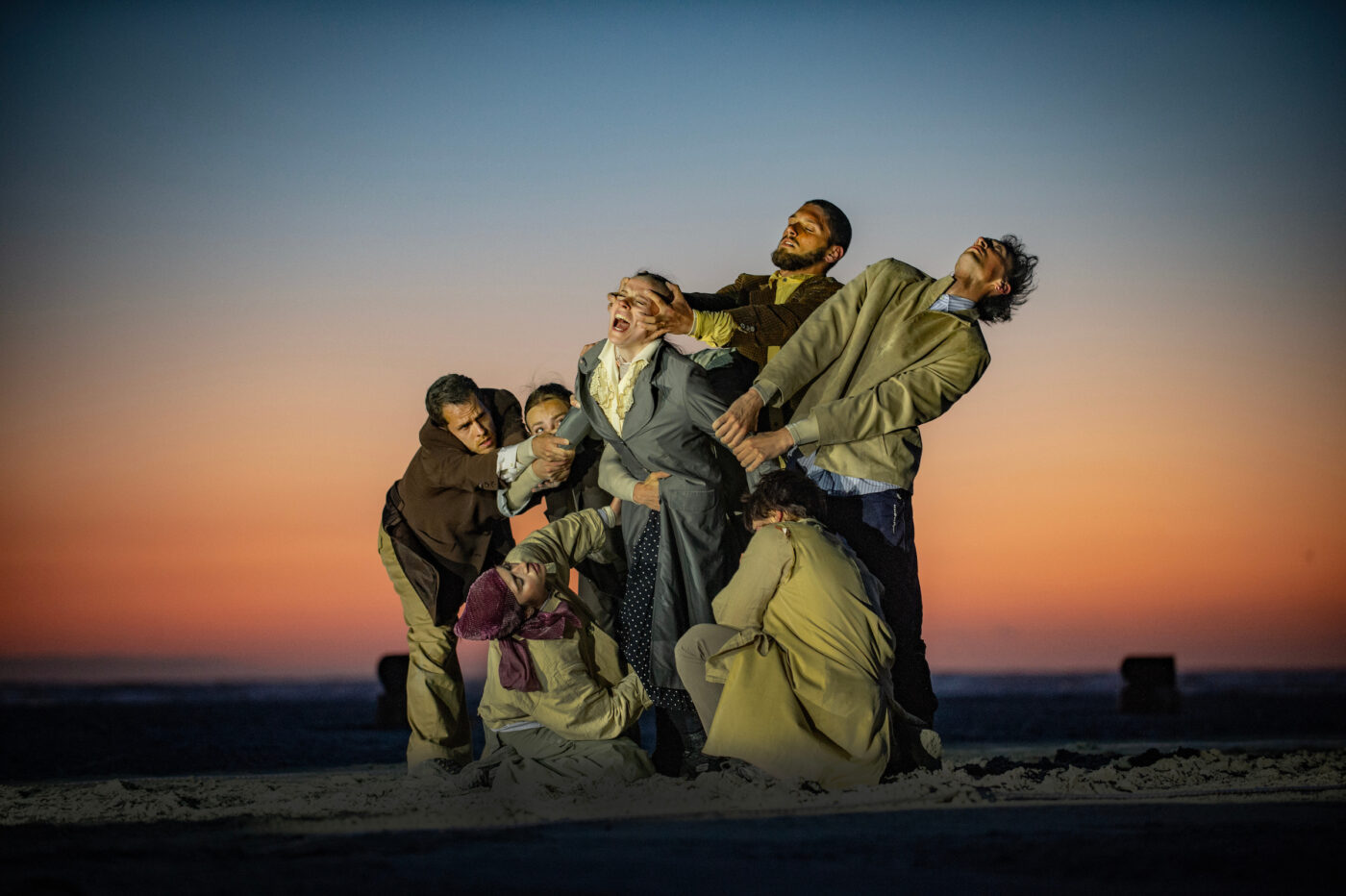 Groep dansers op het strand die iemand tegenhoudt, als voorbeeld van de BTW-verhoging die de cultuursector beperkt.