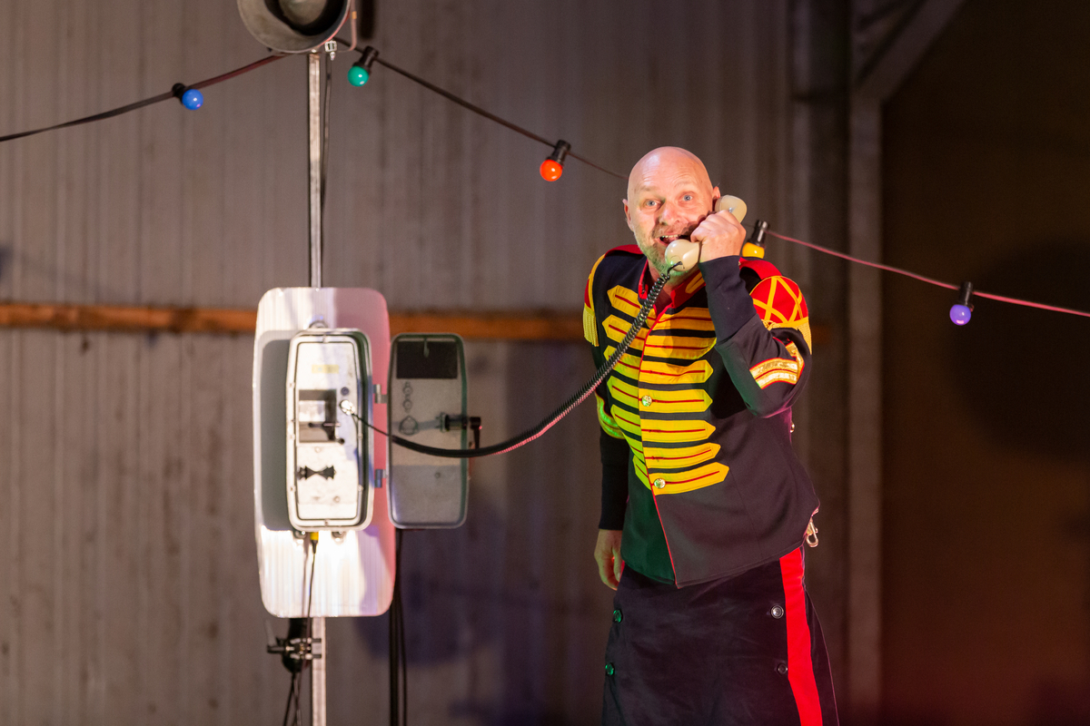 Man in kostuum van muziekvereniging is aan de telefoon.